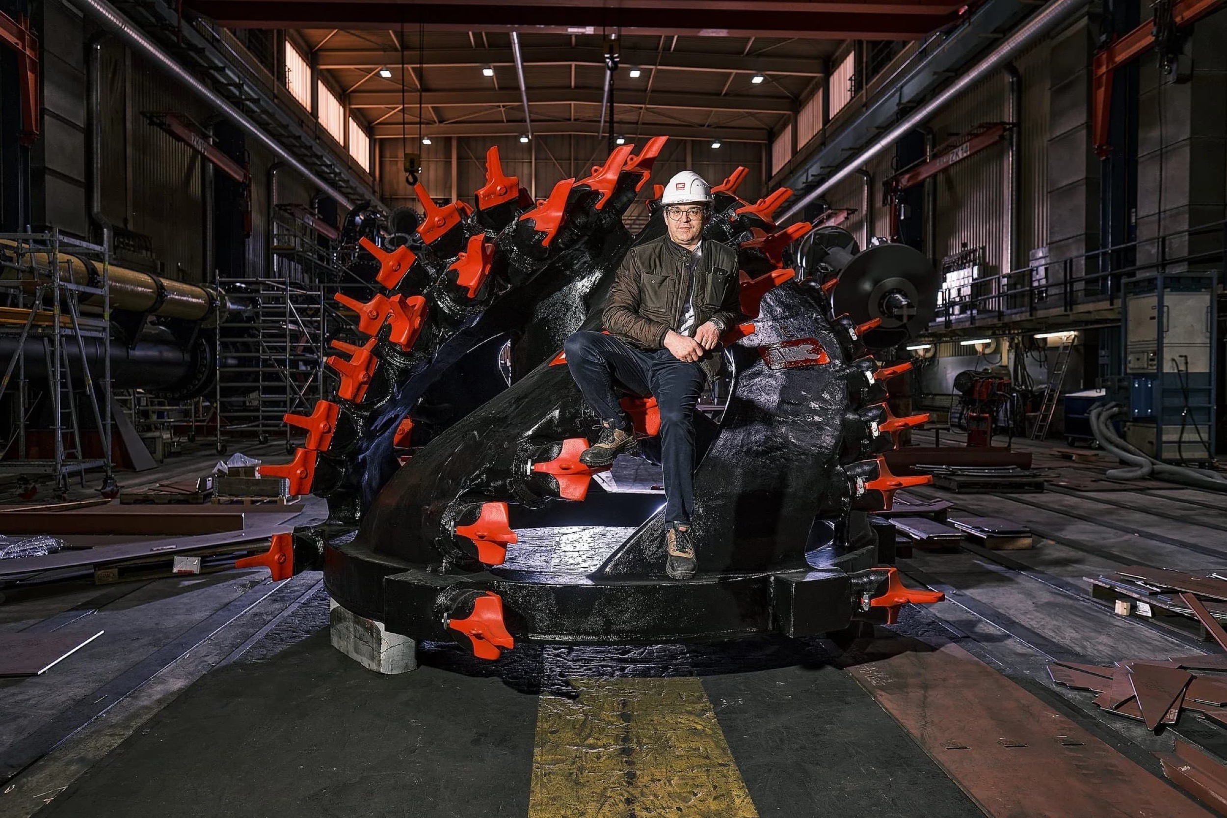 Man met veiligheidshelm zit op grote industriële machine in fabriek, bedrijfsreportage — Stefan Segers Fotografie