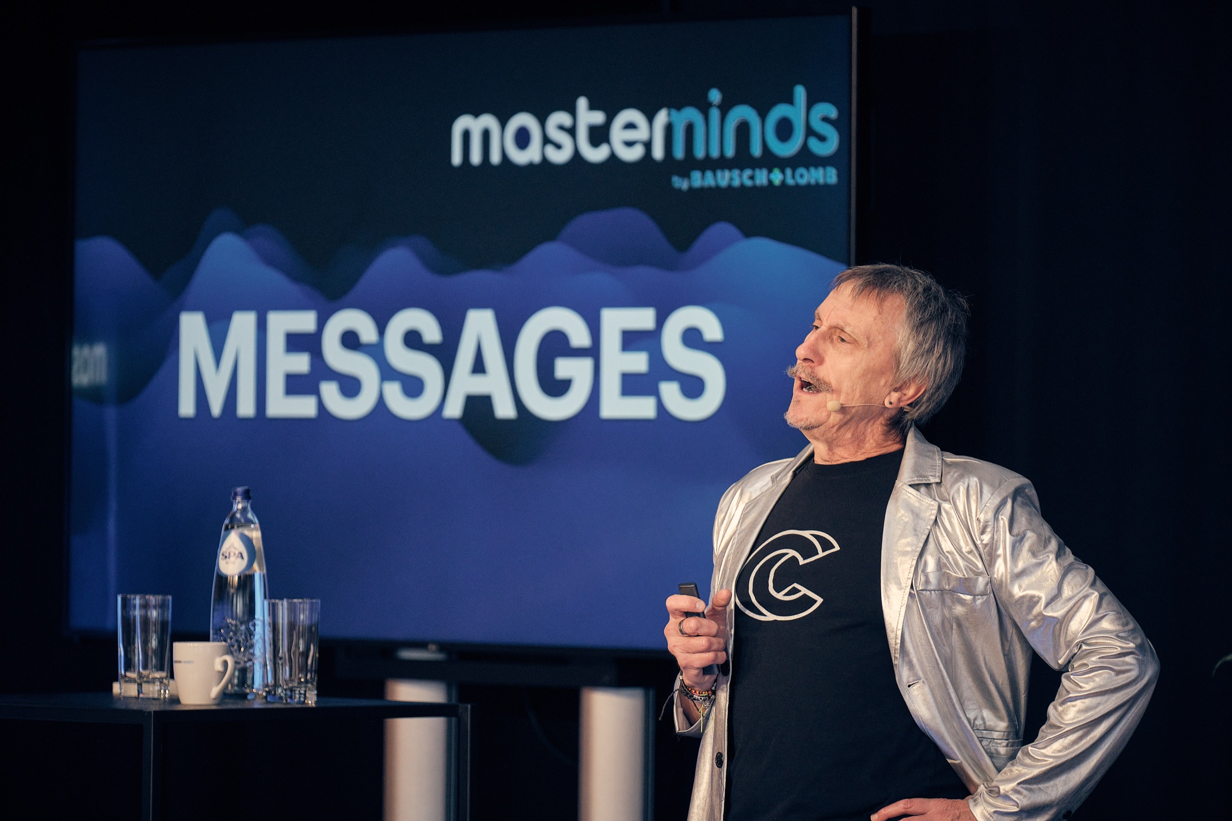 Spreker op podium bij Mastermind Messages event, zilverkleurig jasje, Bausch+Lomb congress Zaventem — Stefan Segers Fotografie