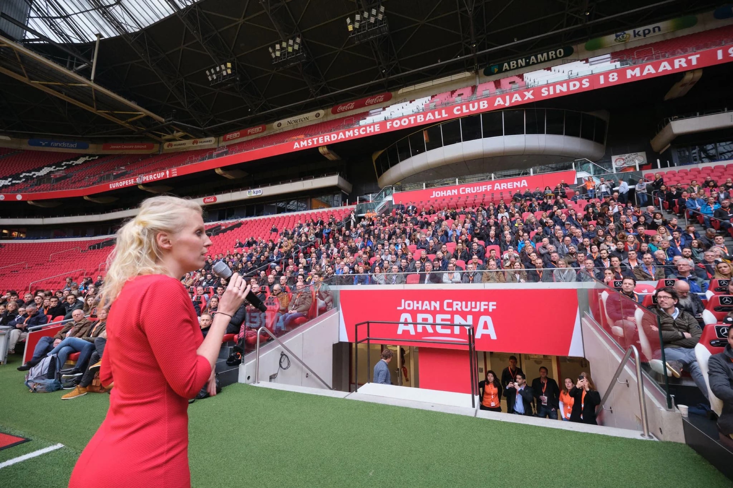 Vrouw in rood spreekt voor volle tribunes op voetbalstadion, Johan Cruiff Arena Amsterdam — Stefan Segers Fotografie