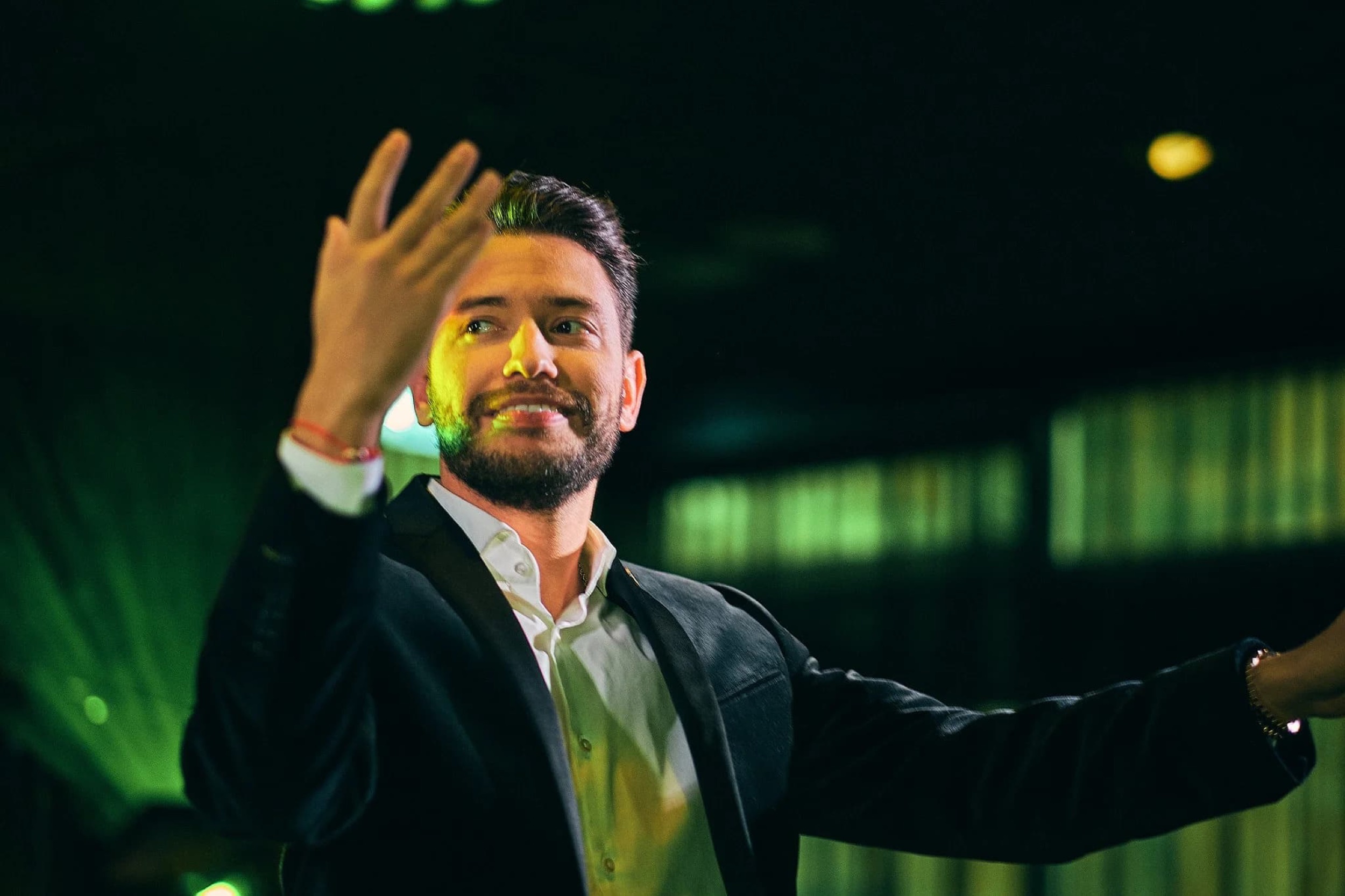 Man in donker pak spreekt passioneel op zakelijk evenement met groene sceneverlichting — Stefan Segers Fotografie
