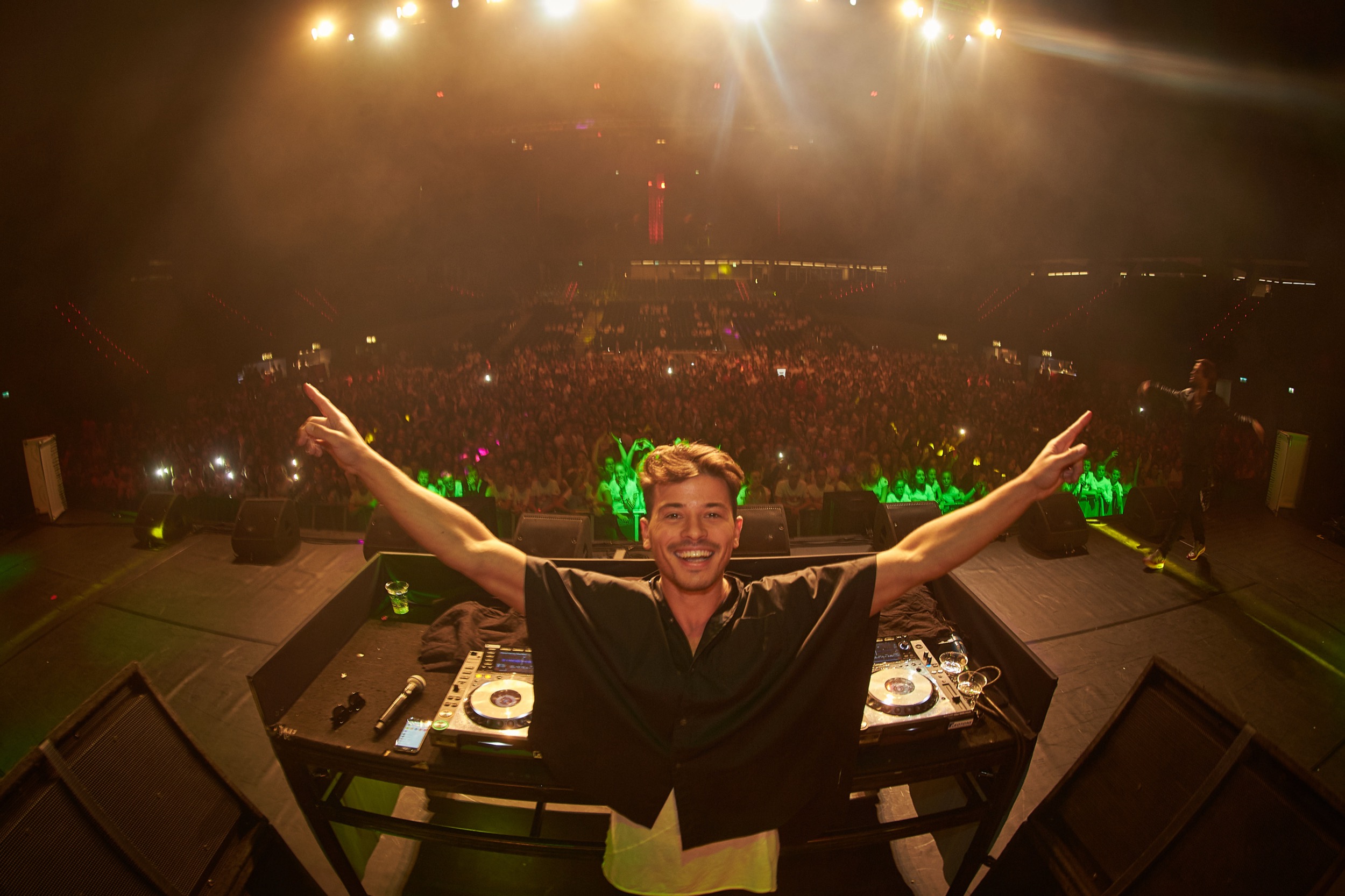 DJ triomfantelijk met armen omhoog achter draaitafel, volgelopen zaal Dance 4 Life event Rotterdam — Stefan Segers Fotografie