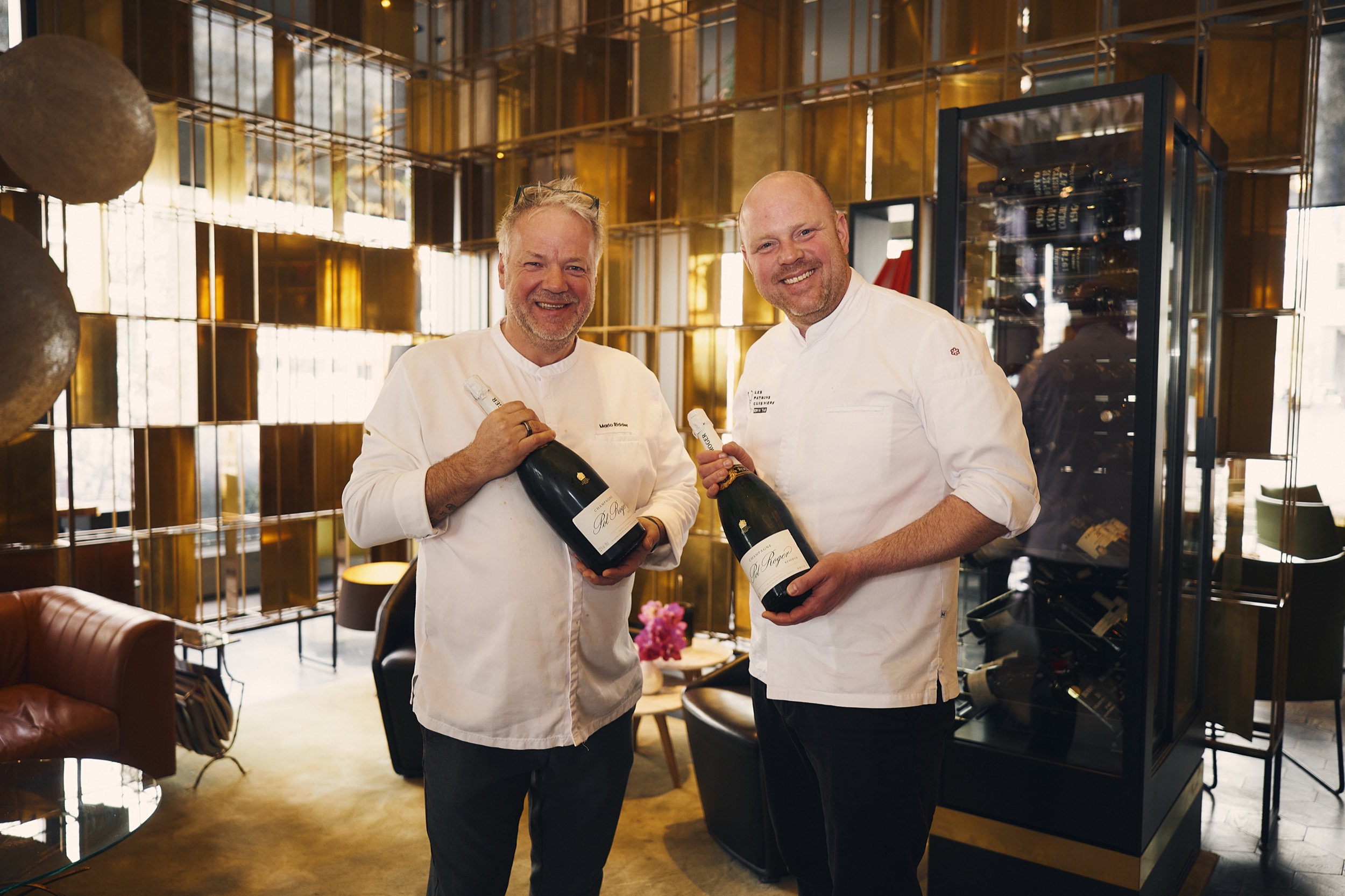 Twee chefs in witte koks togas houden wijneflessen vast in luxe restaurantomgeving, Rotterdam — Stefan Segers Fotografie