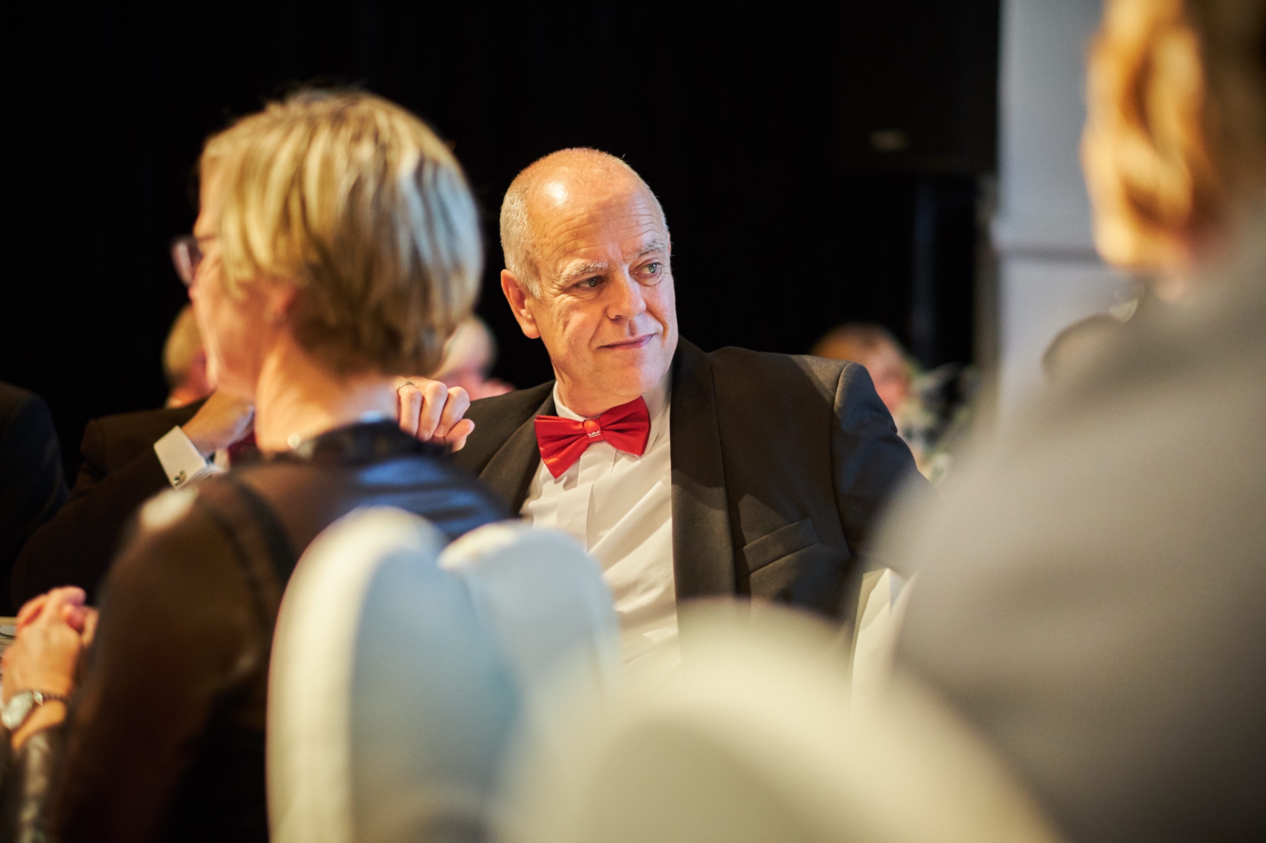 Man in smoking met rode strik in gesprek tijdens gala diner, jubileumfeest IRO Rotterdam — Stefan Segers Fotografie