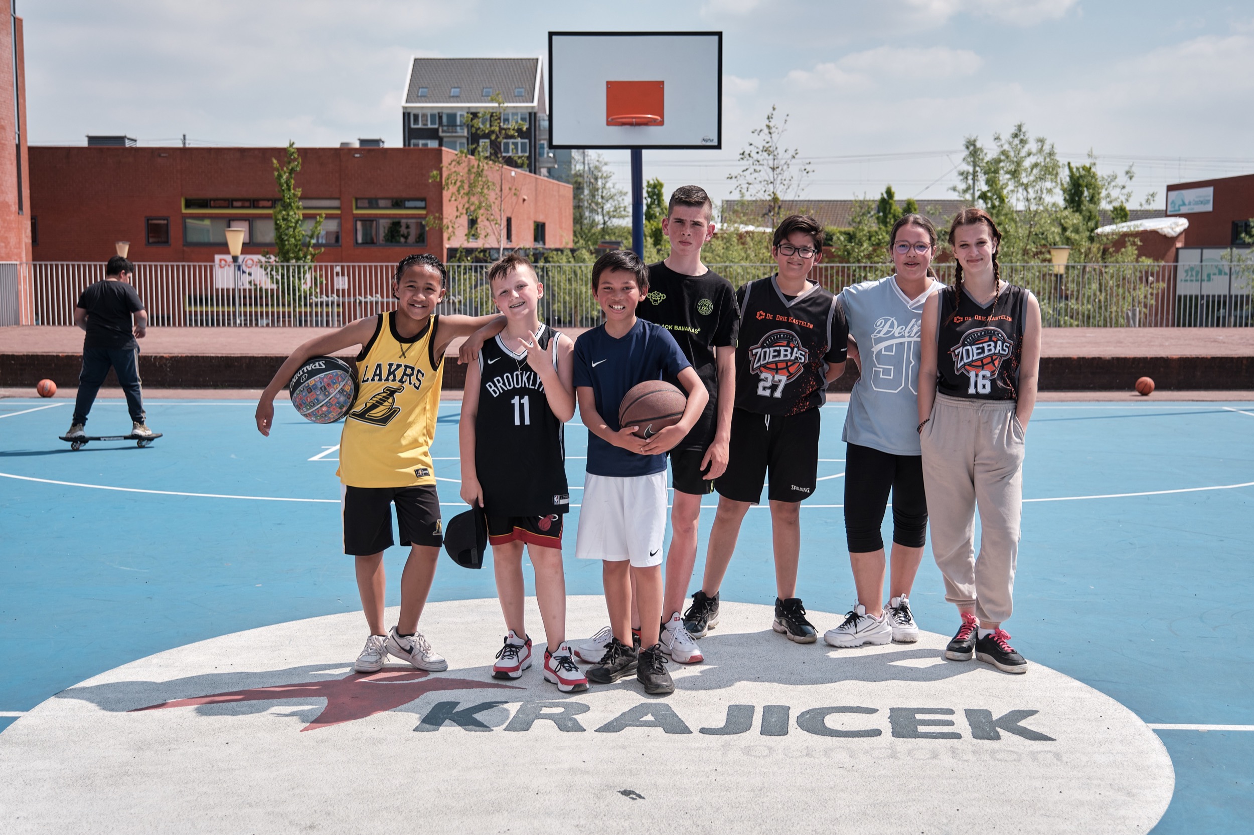 Groep jongeren poseren samen op basketbalveld Krajecek Foundation Zanzibarplein Zoetermeer — Stefan Segers Fotografie