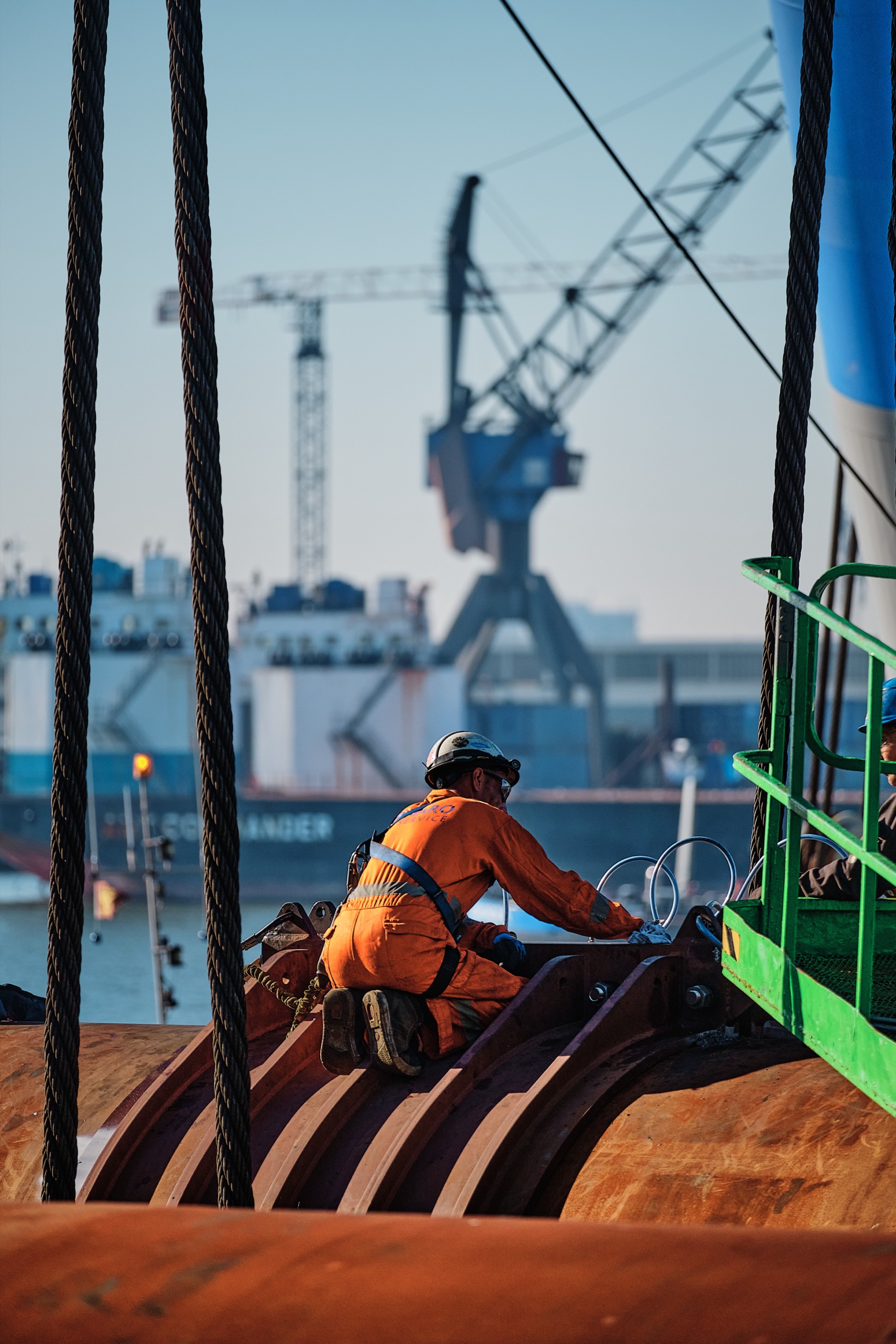 Werknemer in oranje veiligheidskleding plaatst spudpalen op schip, havenkraan op achtergrond, Krimpen aan den IJssel — Stefan Segers Fotografie