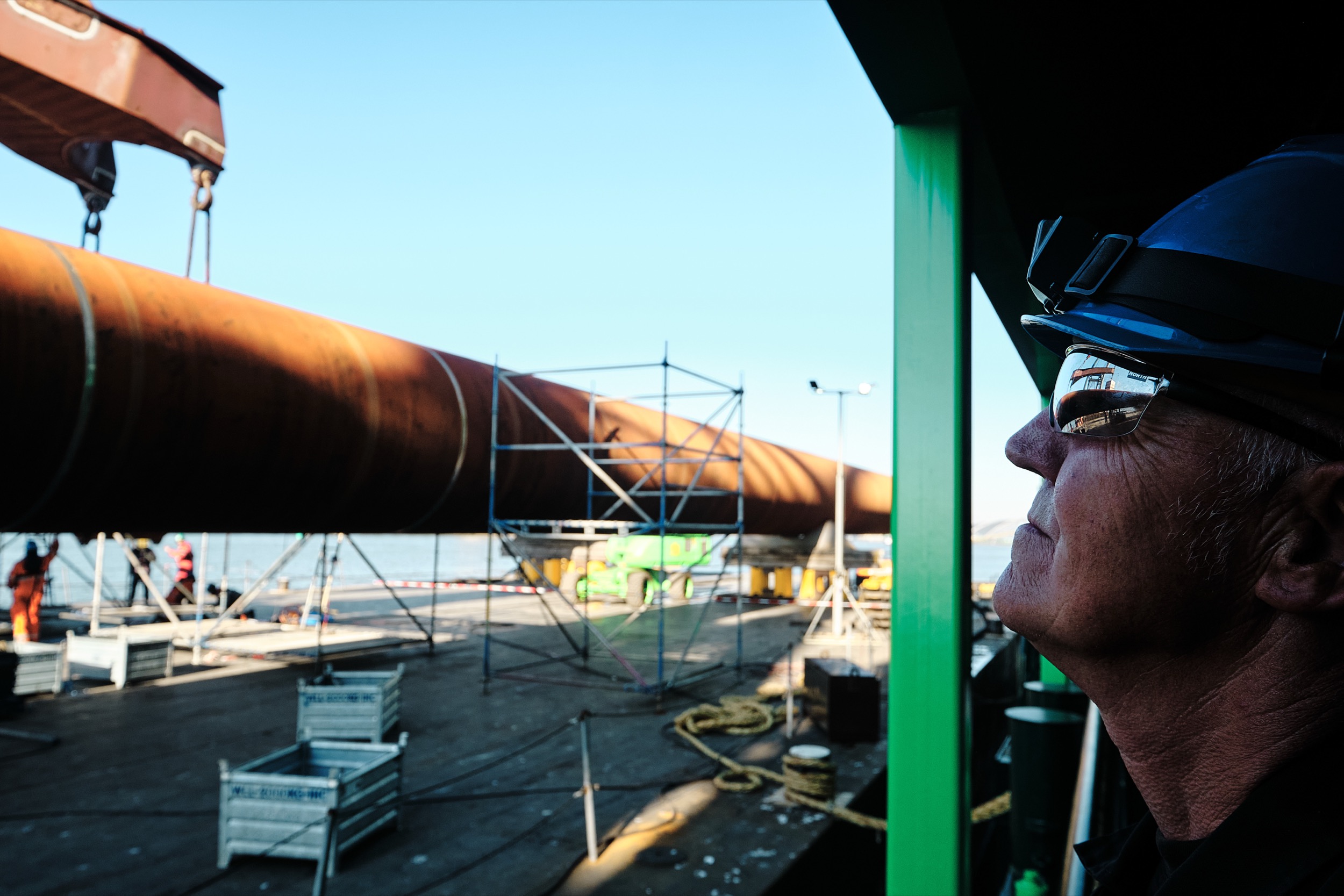 Werker met helm kijkt toe bij plaatsing spudpalen op Deme Spartacus, Krimpen aan den IJssel — Stefan Segers Fotografie