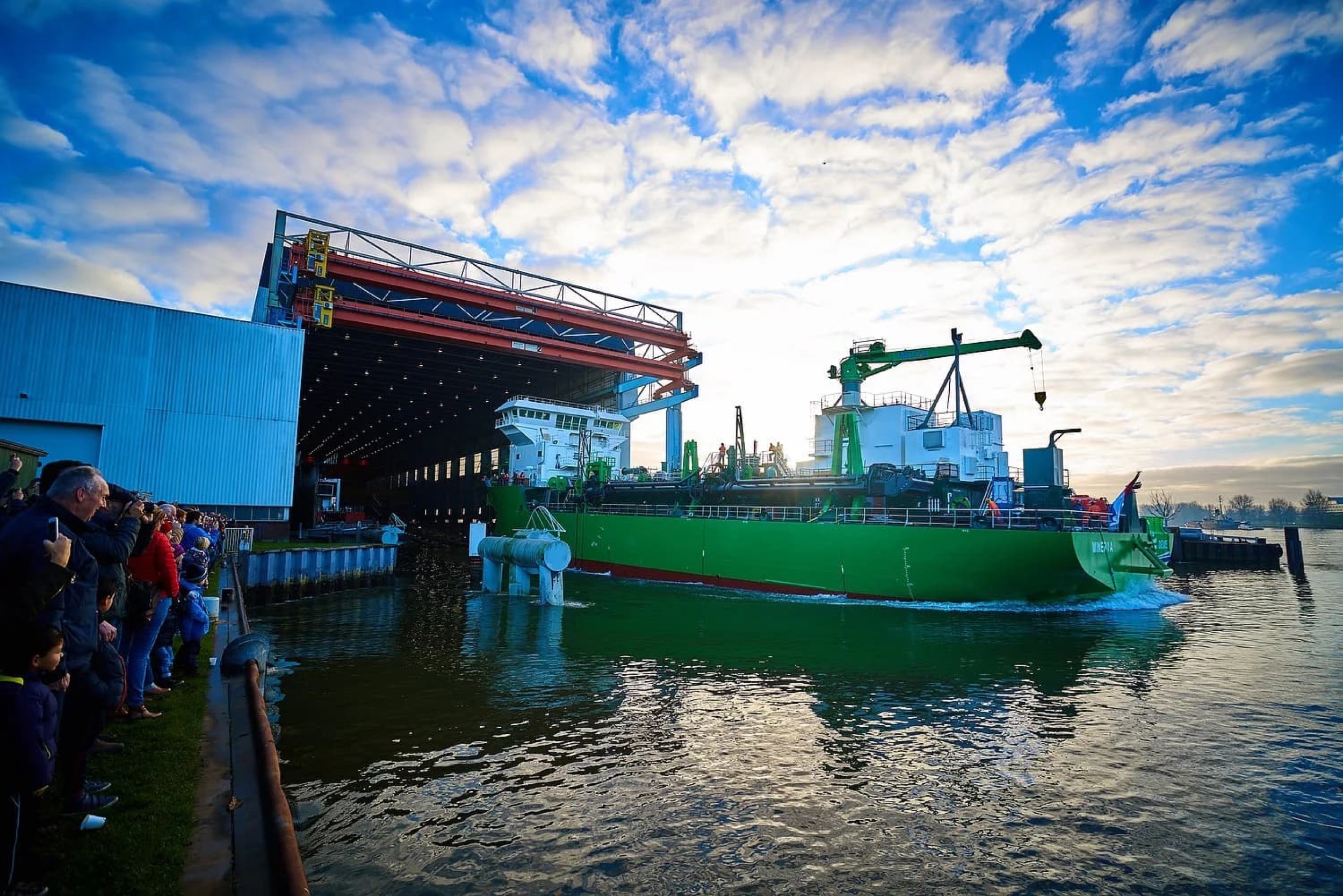 Groene vrachtschip verlaat scheepswerf met toeschouwers aan kade, industriële kraaninfrastructuur — Stefan Segers Fotografie
