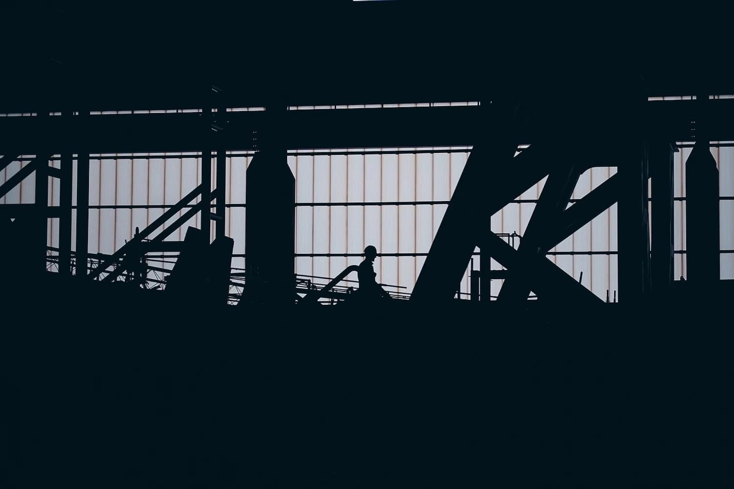 Silhouet van werknemer in industriële fabriekshal met staalstructuren en ramen, productieomgeving — Stefan Segers Fotografie