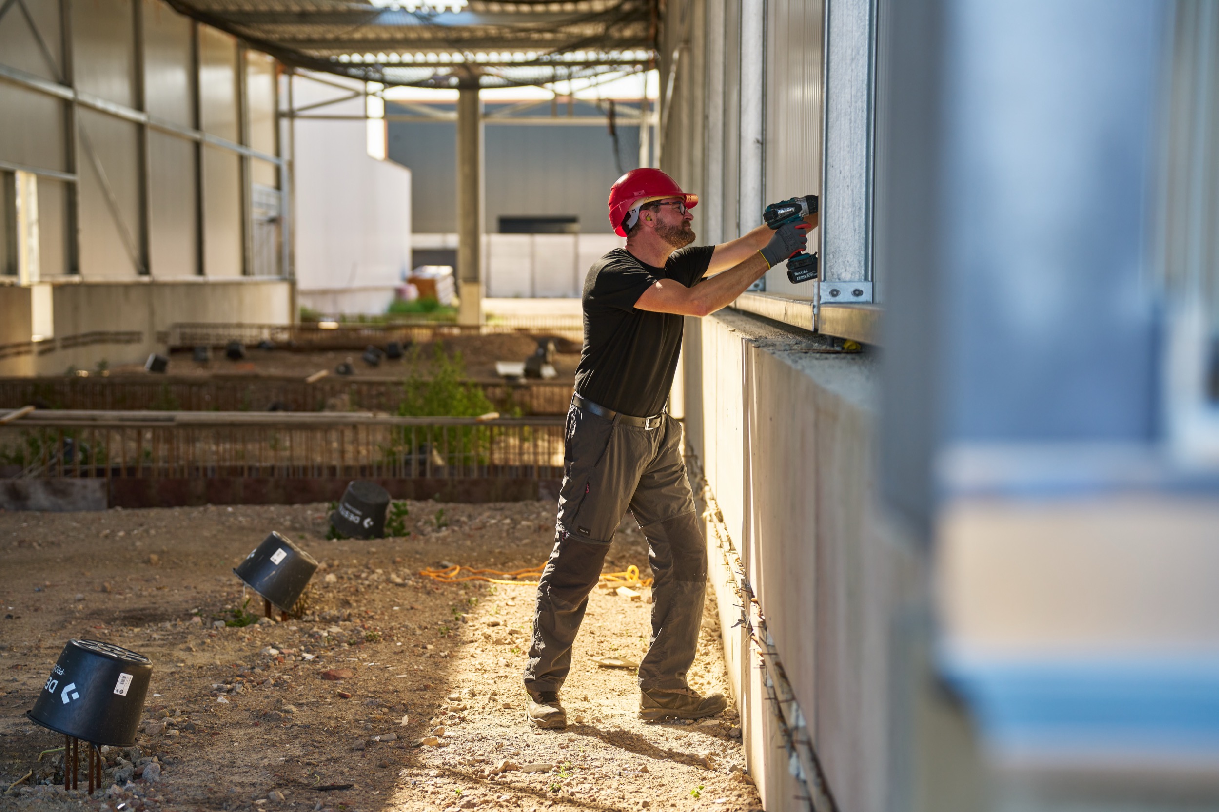Arbeider in rode helm schroeft aan industriële installatie in fabriekshal, Tilburg — Stefan Segers Fotografie