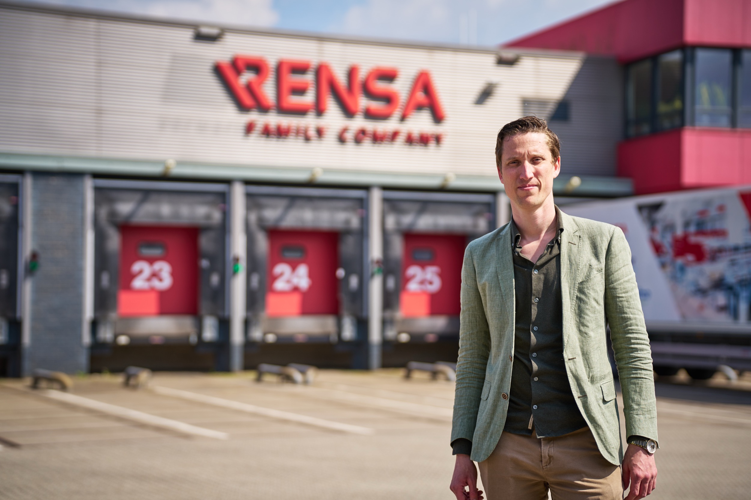 Man in beige blazer staat voor Rensa Family bedrijfsgebouw, Doetinchem — Stefan Segers Fotografie