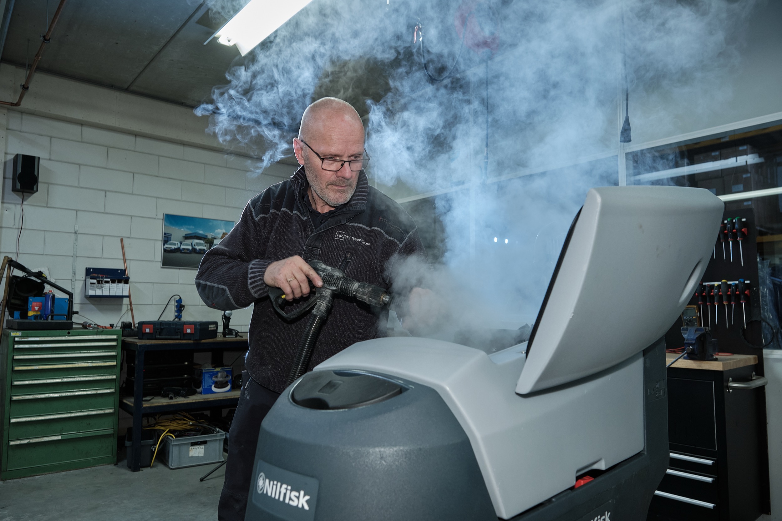 Technicus gebruikt stoomreiniger op witgoedapparatuur in industriële werkplaats Almelo — Stefan Segers Fotografie