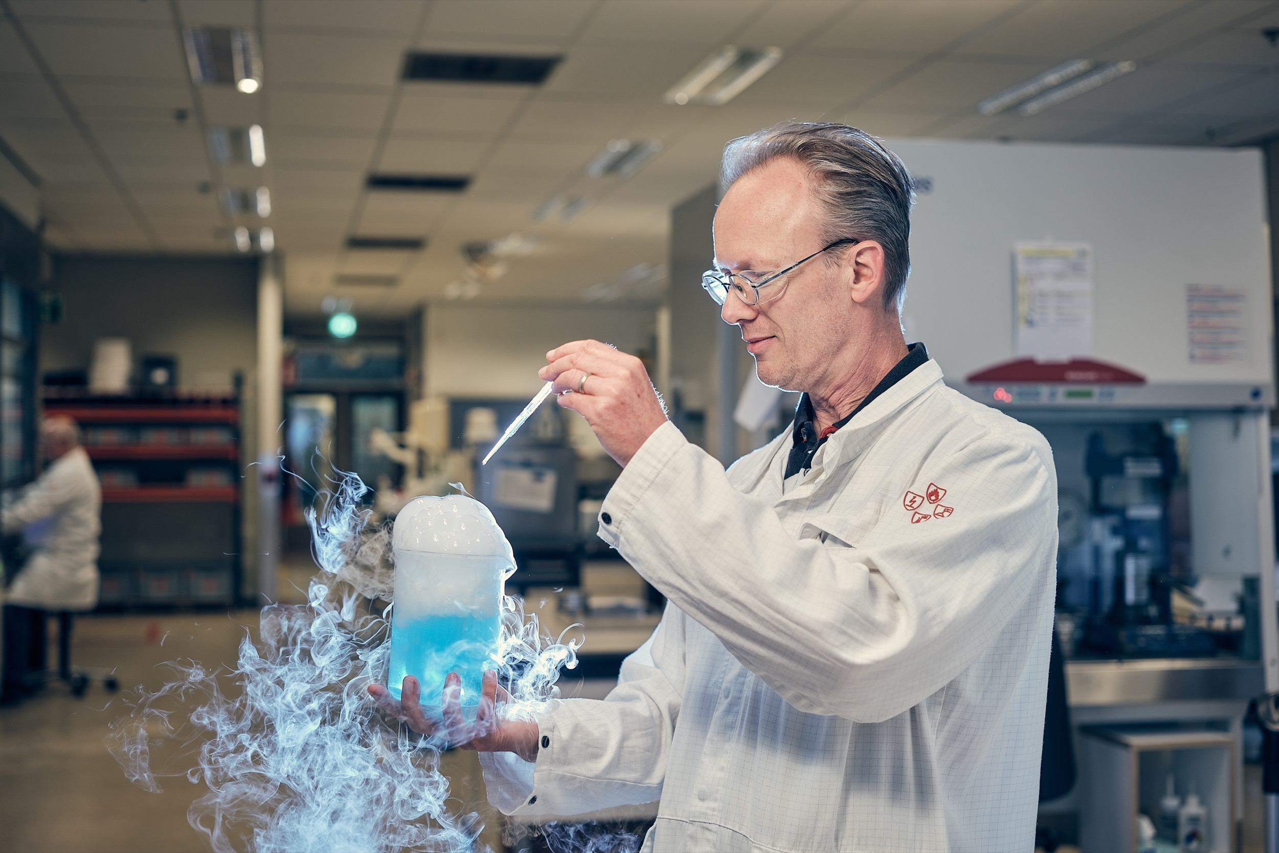 Wetenschapper in witte laboratoriumjas voert experiment uit met droogijs en blauwe vloeistof, BASF-onderzoekslaboratorium — Stefan Segers Fotografie