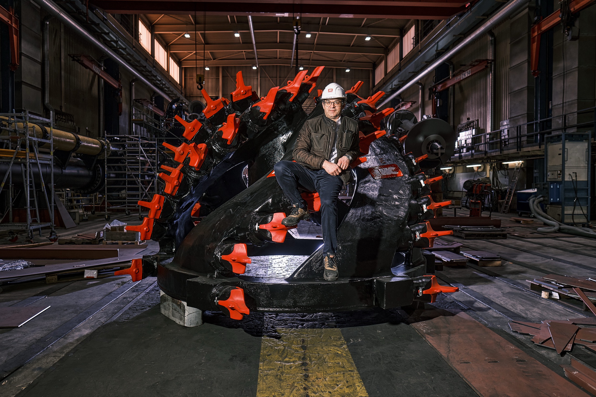 Werknemer in witte helm inspecteert rode cutterkop in fabriekshal Royal IHC, Kinderdijk — Stefan Segers Fotografie