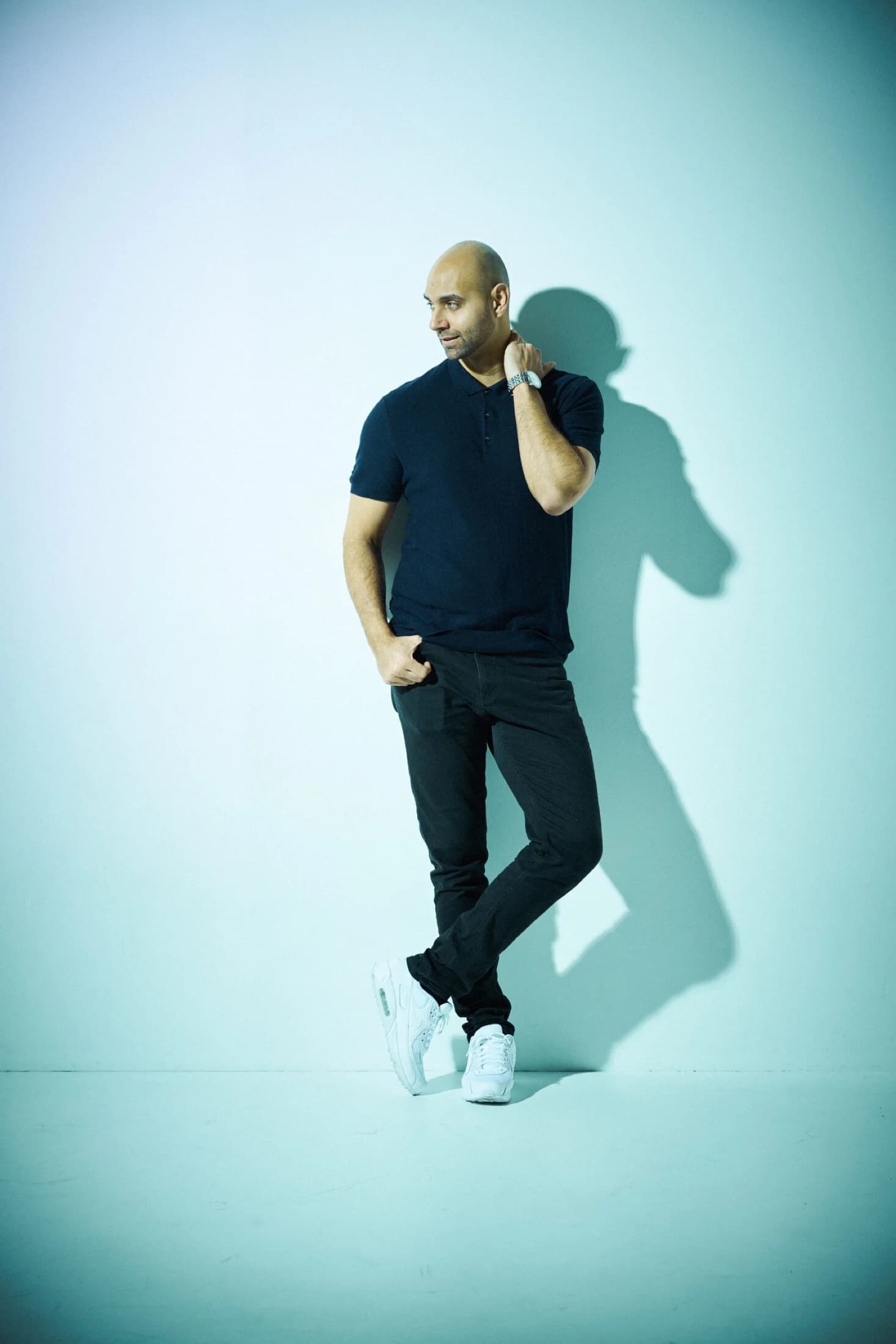 Man in marineblauw shirt en jeans staat tegen lichte achtergrond in casual-professionele pose, portret — Stefan Segers Fotografie