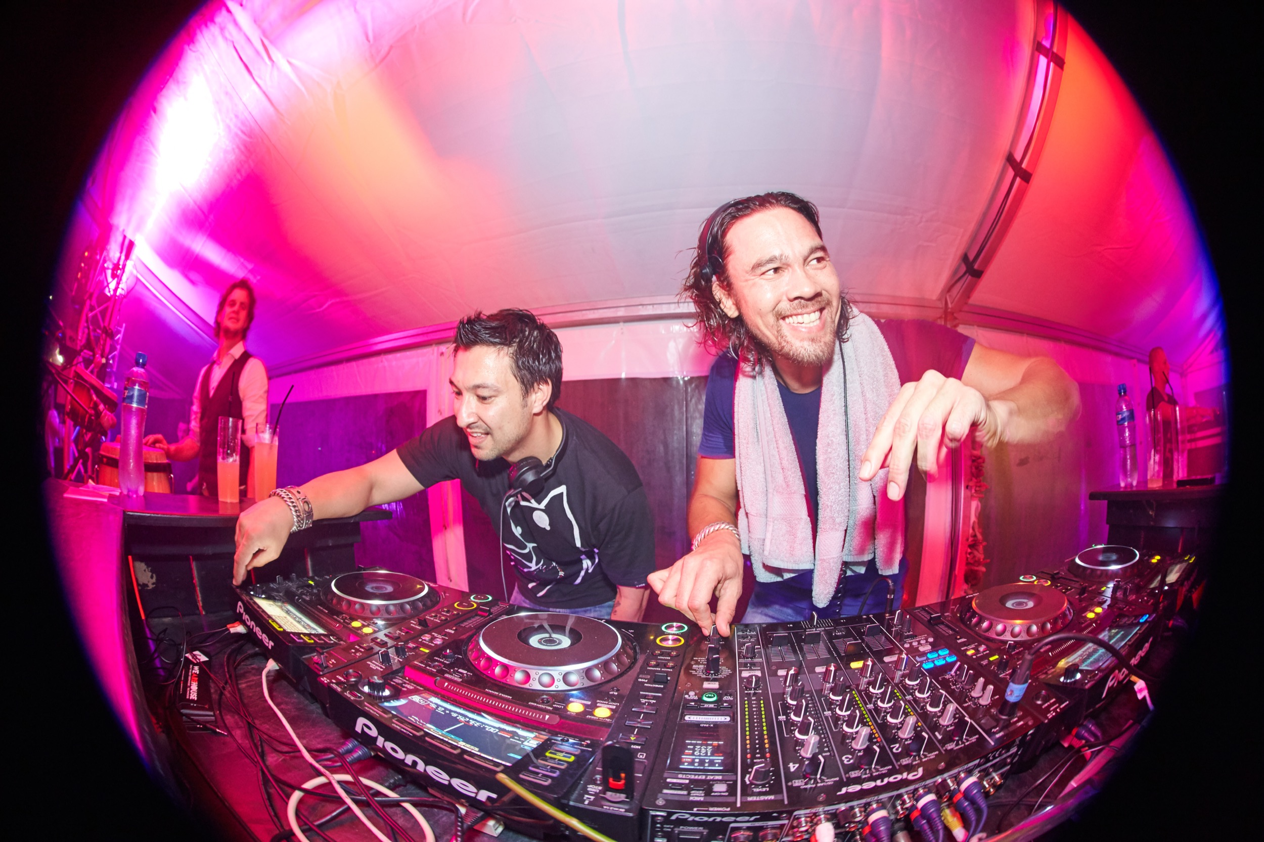 Twee DJ's achter mengpaneel in roze verlichte booth, feestsfeer, Scheveningen party — Stefan Segers Fotografie