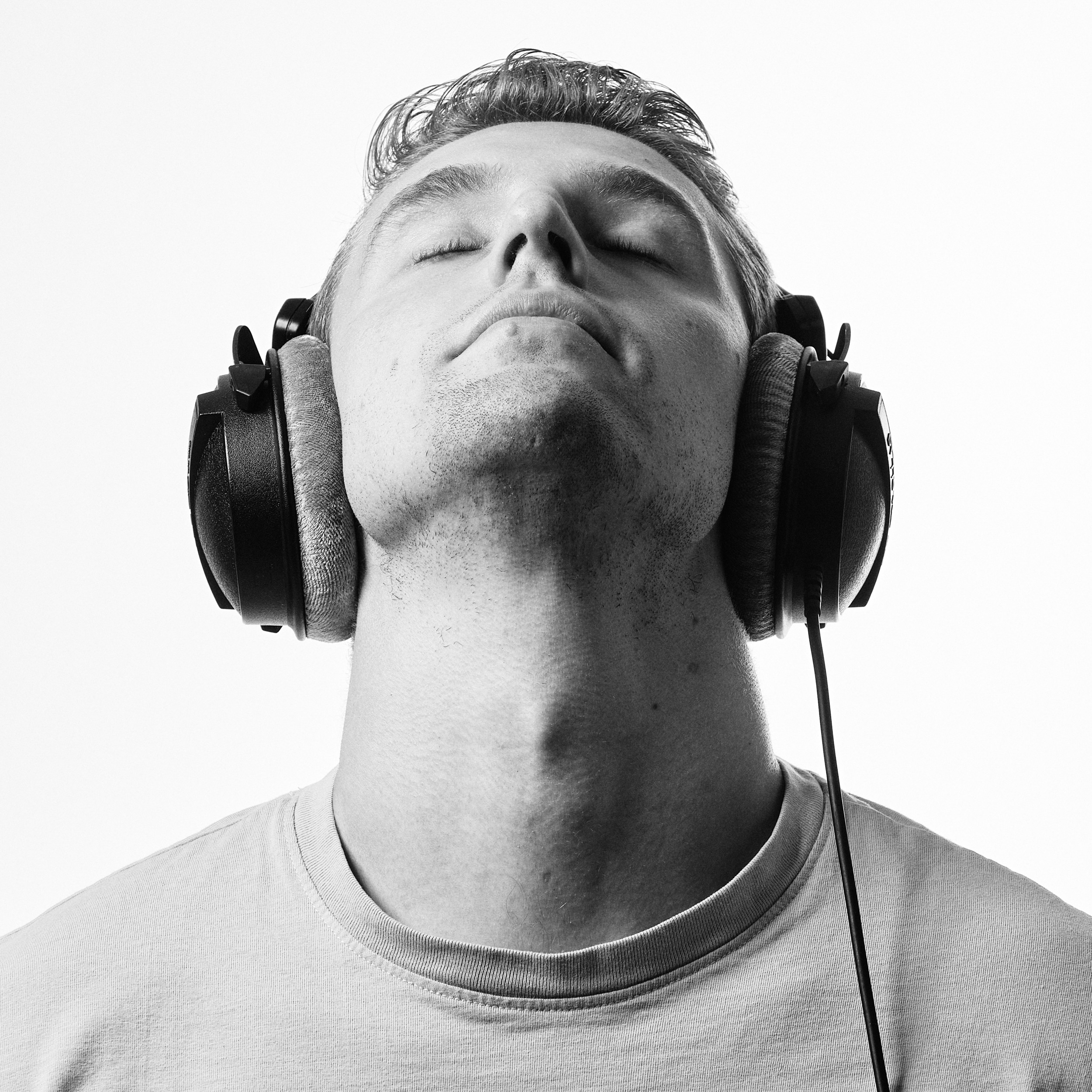 Man met koptelefoon ogen gesloten, studiosfeer zwart-wit, DJ-portret Unphased — Stefan Segers Fotografie