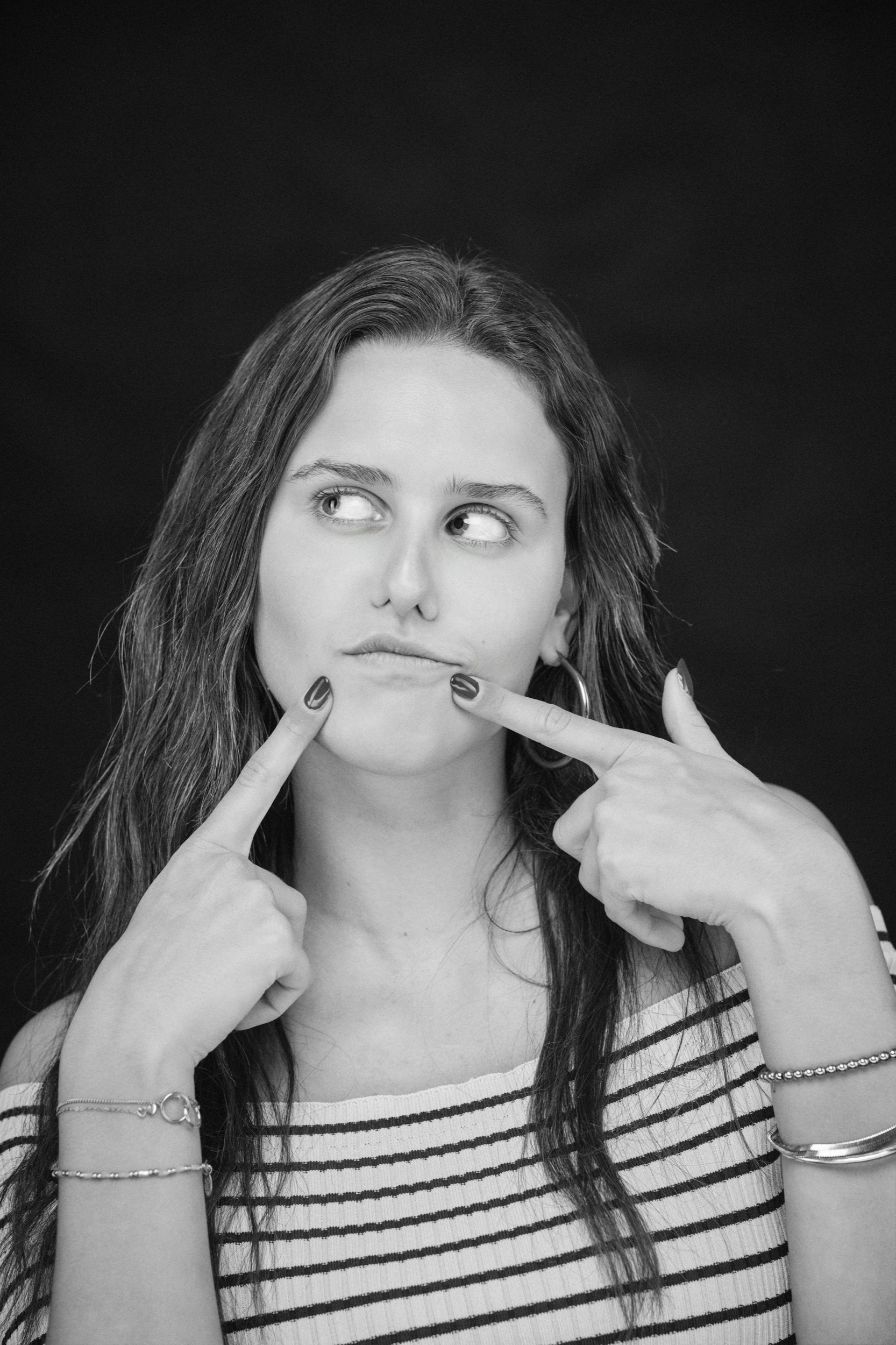 Vrouw in gestreept shirt maakt grappig gezicht met vingers in mond, zwart-wit studioportret — Stefan Segers Fotografie