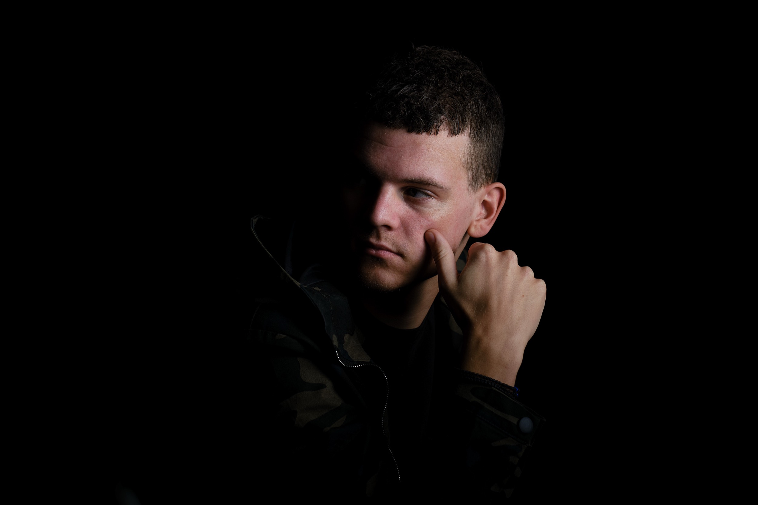 Man in zwart jack kijkt peinzend weg, dramatische studioverlichting, professioneel portret — Stefan Segers Fotografie