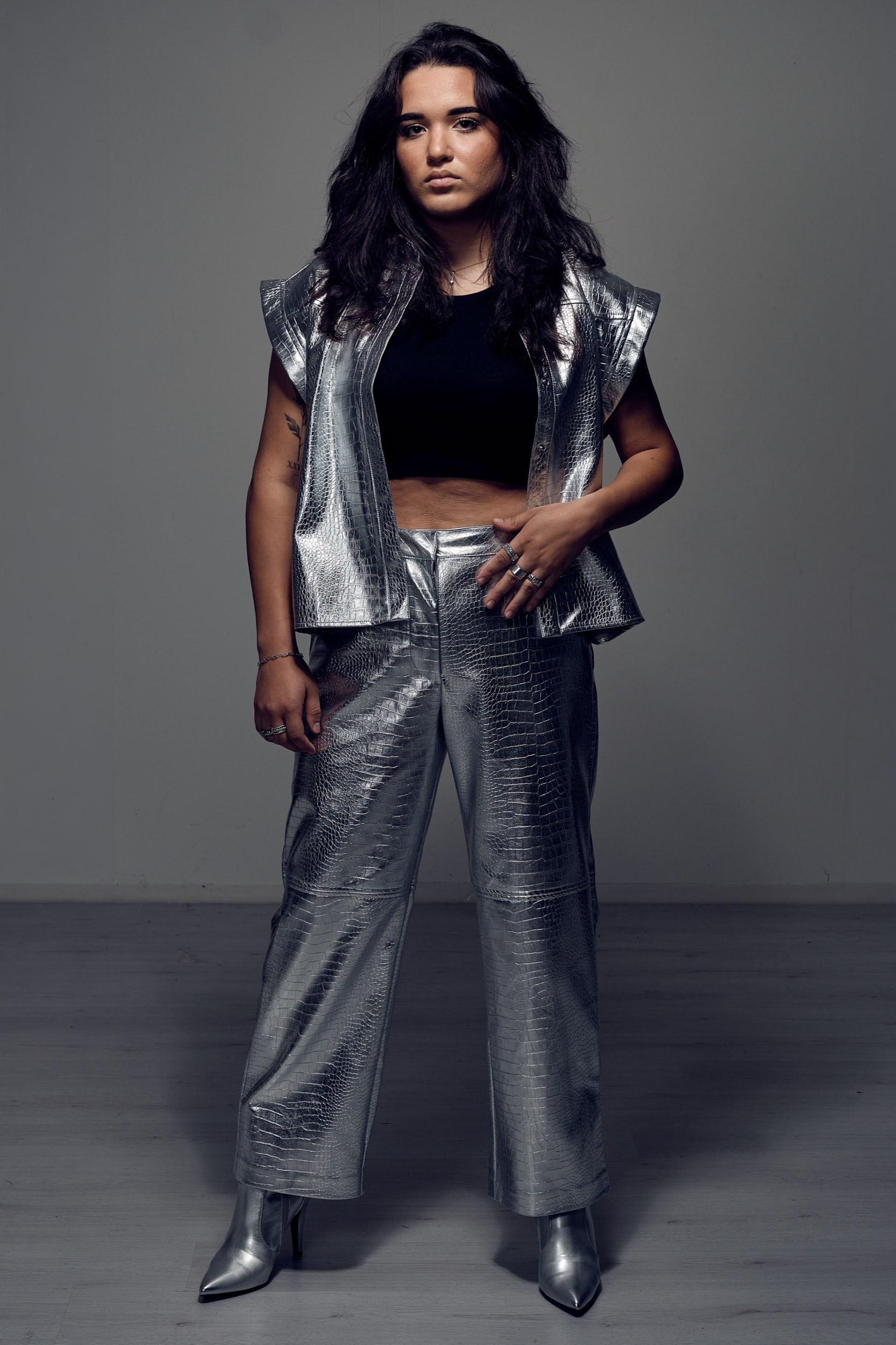 Zangeres in zilver metallic outfit staat zelfverzekerd in fotostudio, professioneel persmateriaal ‚Äî Stefan Segers Fotografie