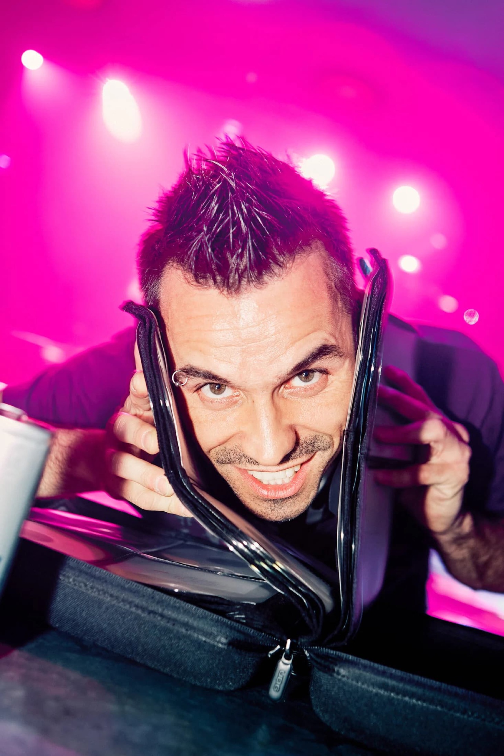 DJ met spiky hairstyle houdt headphones vast tegen roze neonverlichting, energieke studiosfeer — Stefan Segers Fotografie