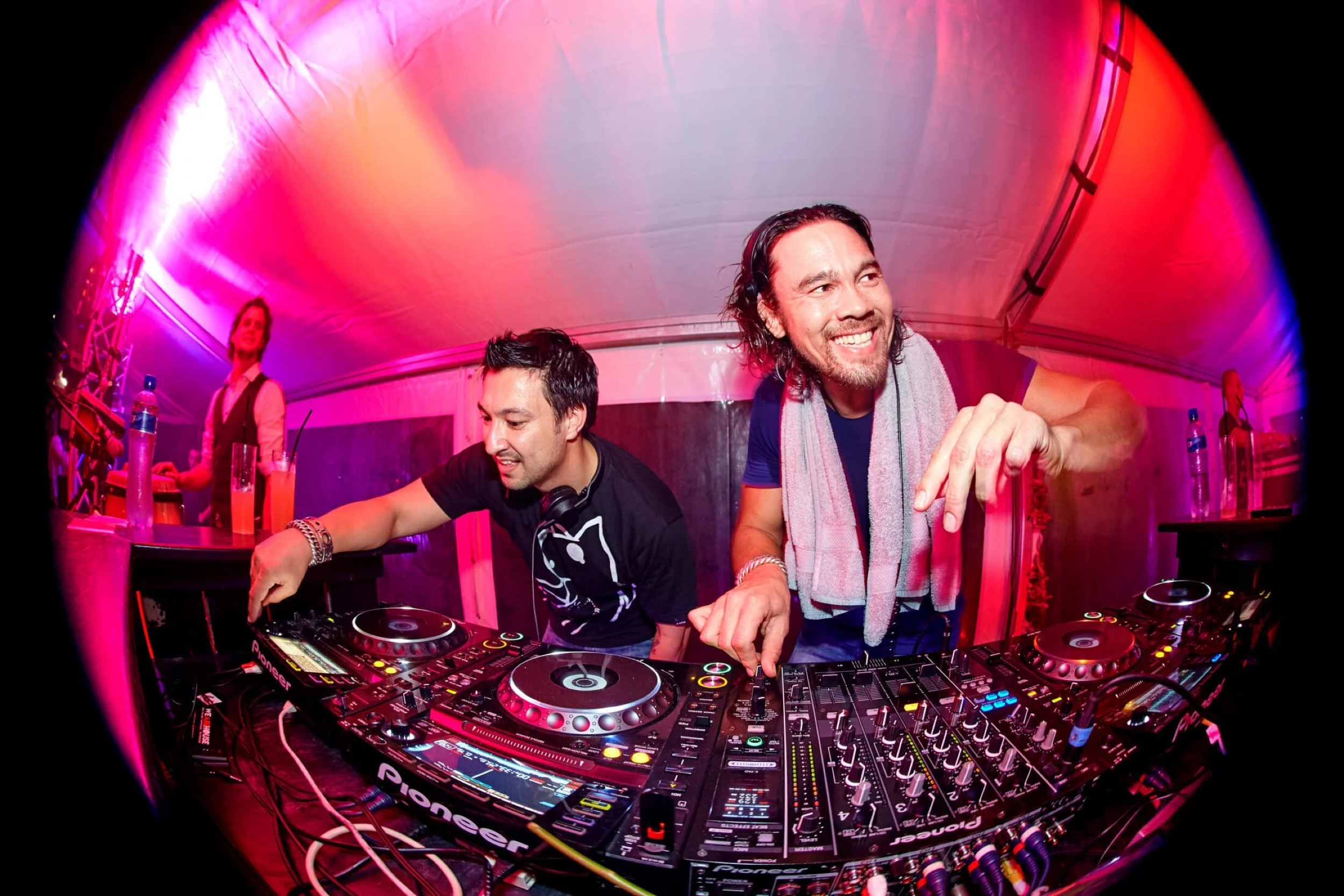 Twee DJ's achter draaitafels in roze neon verlichte clubkabine, energieke evenementfotografie — Stefan Segers Fotografie