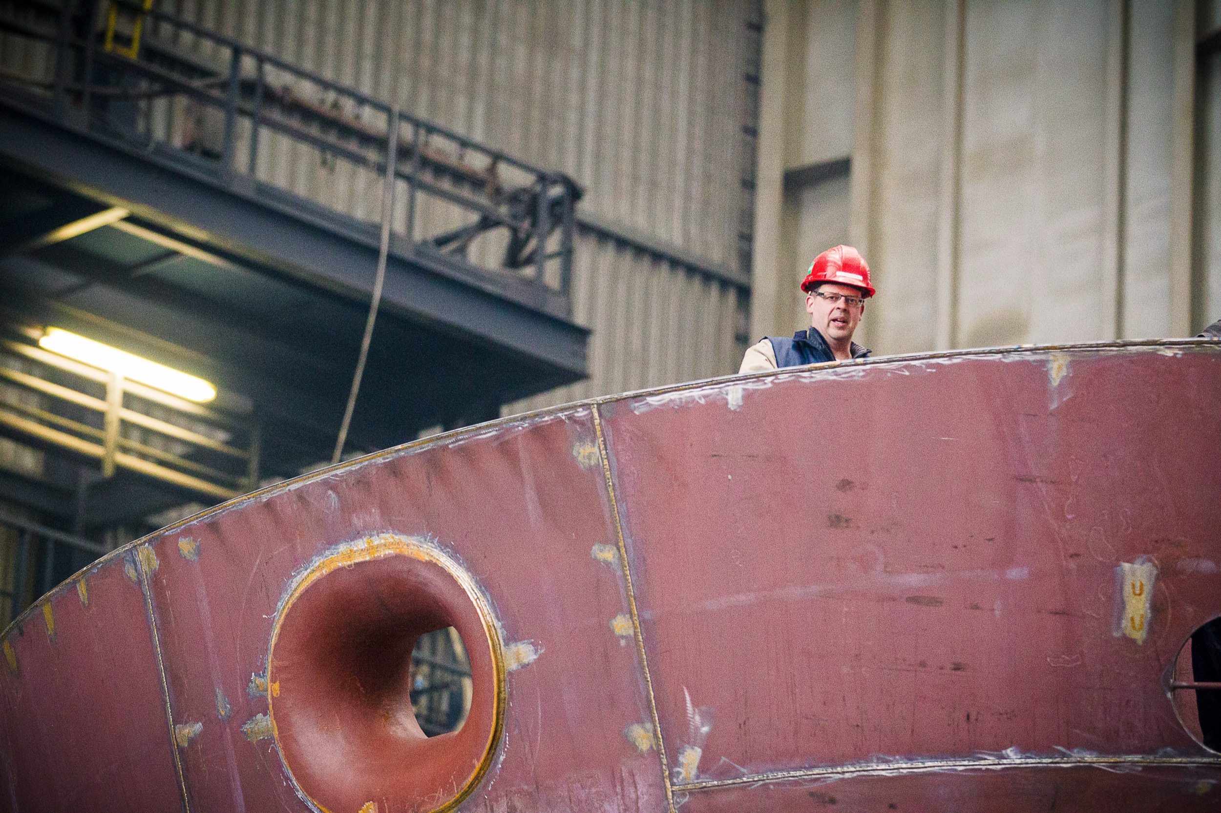 Werknemer in rode veiligheidshelm op scheepsromp bij IHC Krimpen aan den IJssel, industrieel — Stefan Segers Fotografie