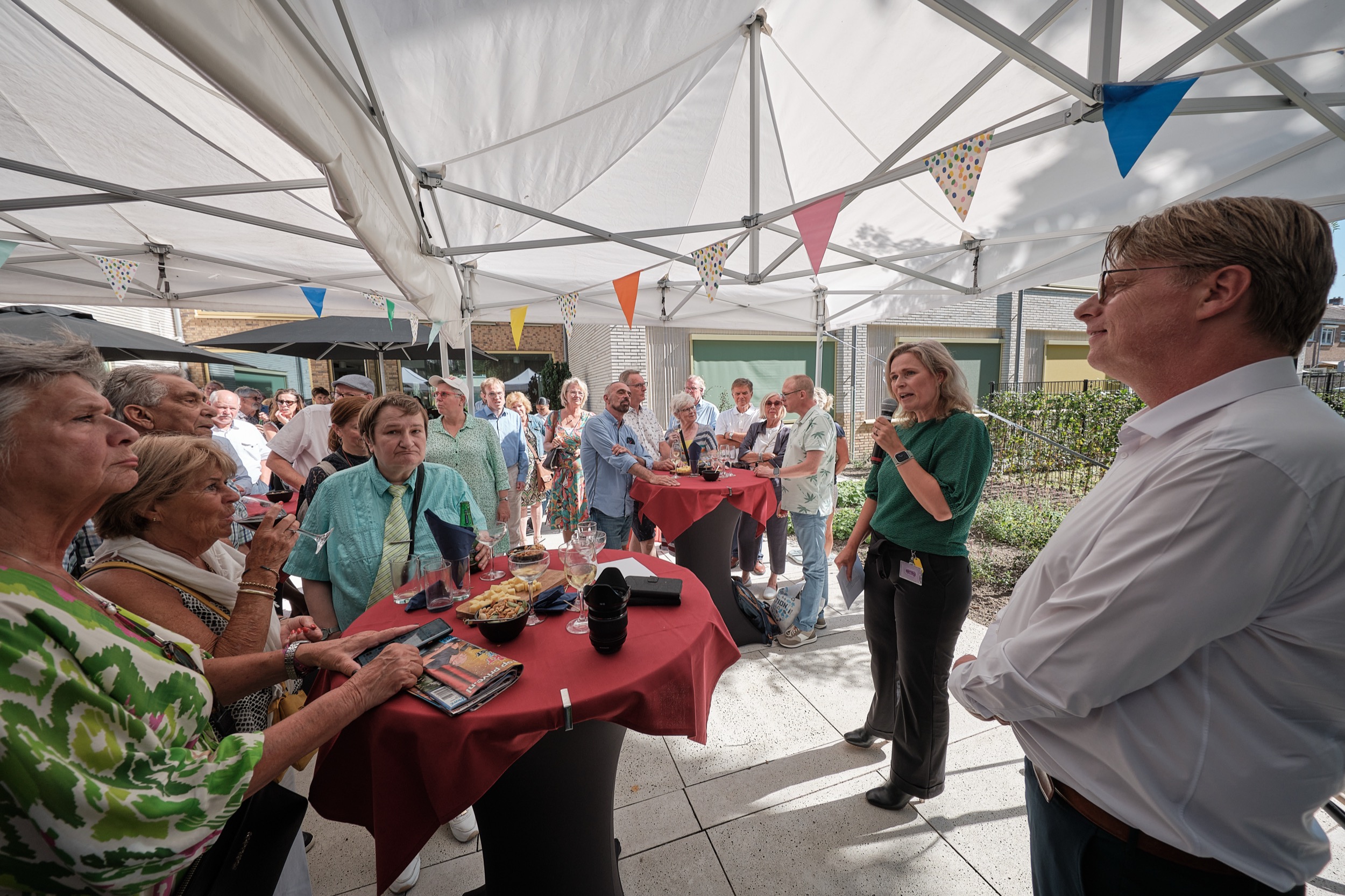 Groep gasten luistert naar sprekers tijdens officiële opening onder tent, Hoekstee Rotterdam — Stefan Segers Fotografie